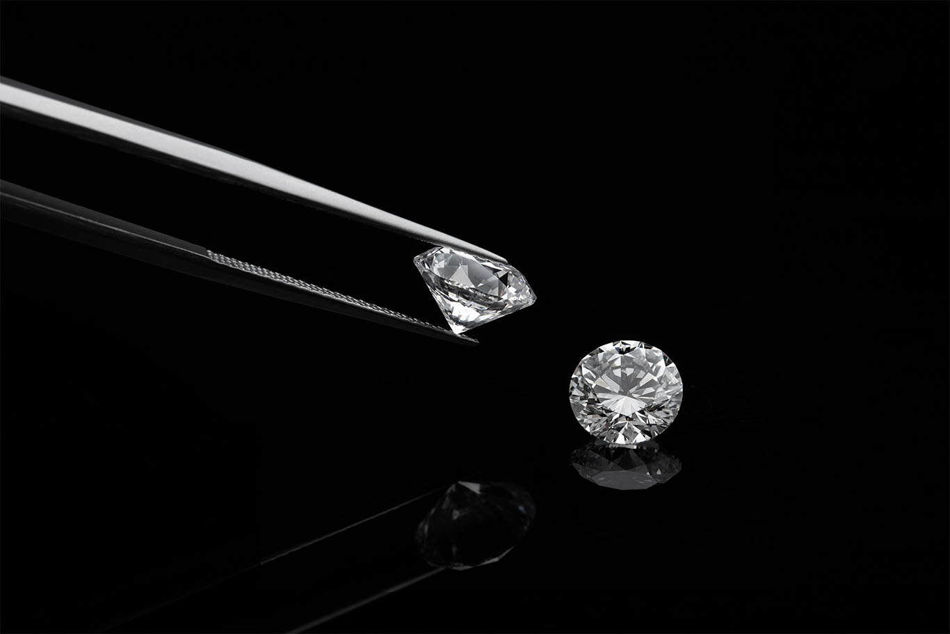 picture of two diamonds and tweezers on black background